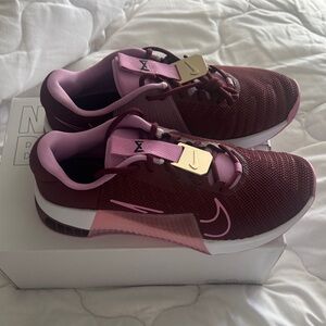 Women's Nike Metcon 9 training shoes in a burgundy and pink colorway.